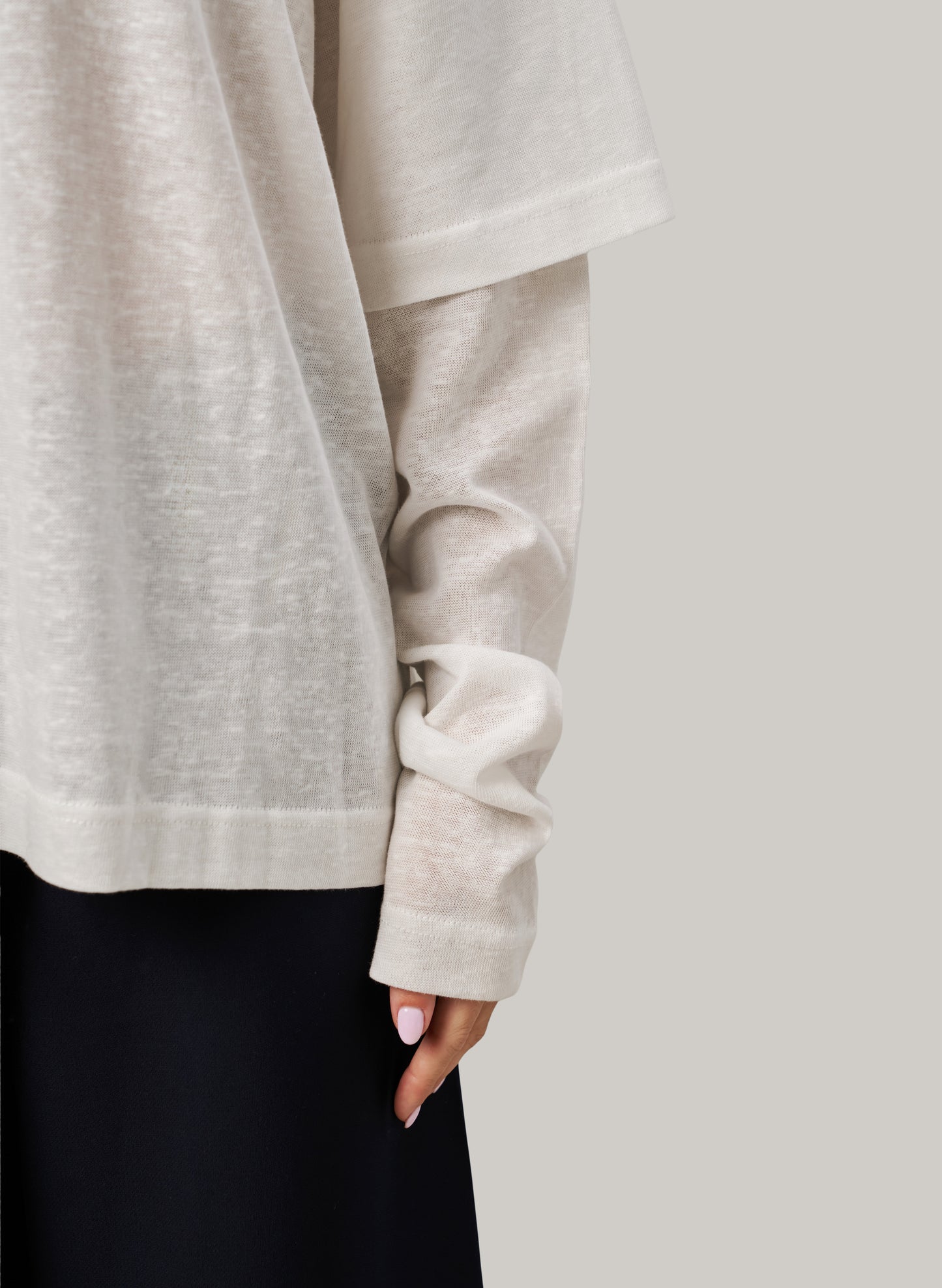 Close-up of a person wearing a white sweater with a plain background