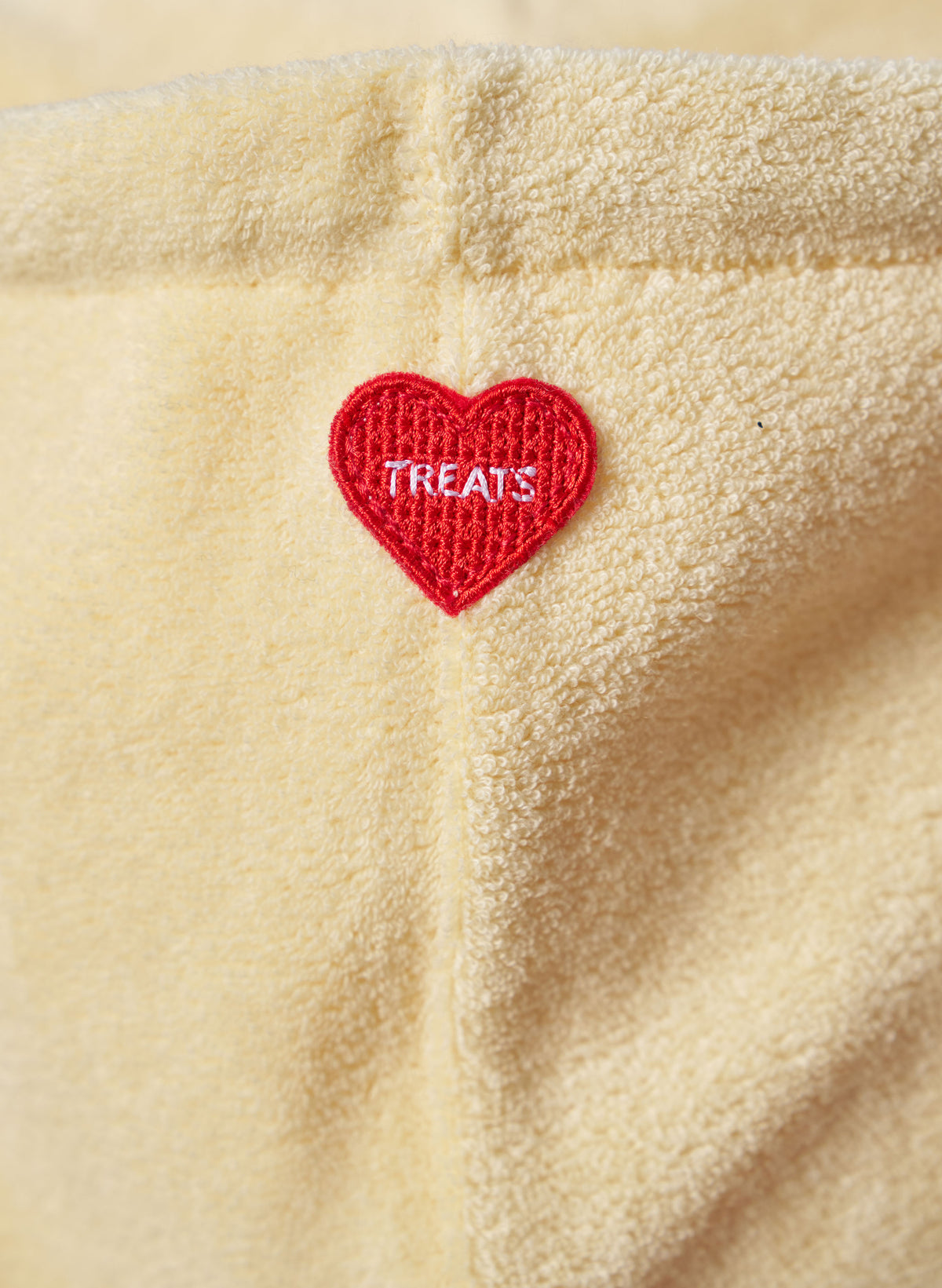 Red heart-shaped patch with 'TREATS' text on lemon fleece fabric