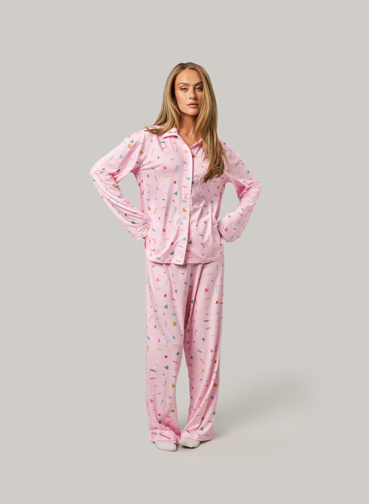 Woman wearing a pink pajama set with a pattern on a gray background