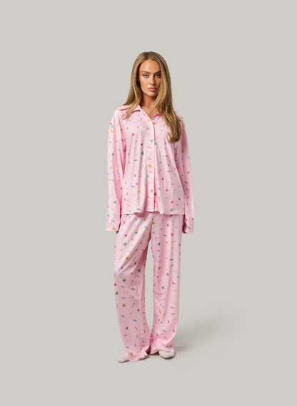 Woman wearing pink pajamas with a pattern on a gray background