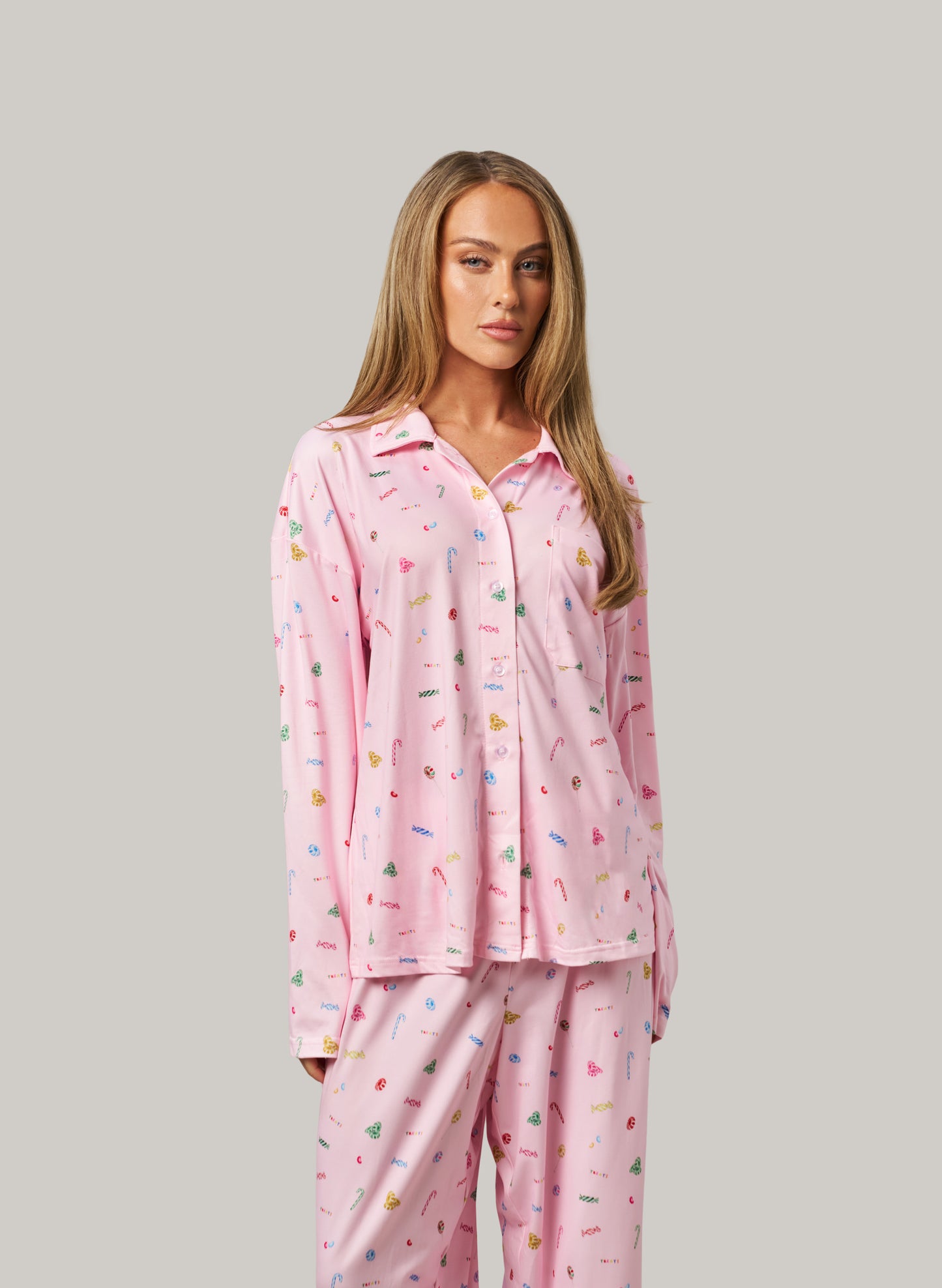 Woman wearing pink pajamas with colorful patterns on a gray background
