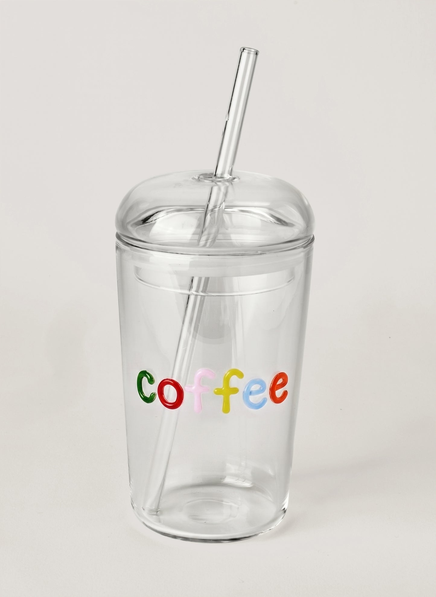 Clear tumbler with colorful 'coffee' text and a straw on a light gray background