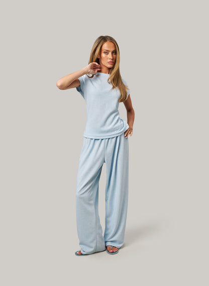 Woman wearing a light blue outfit on a gray background