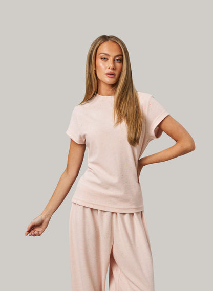 Woman wearing a light pink outfit on a plain background