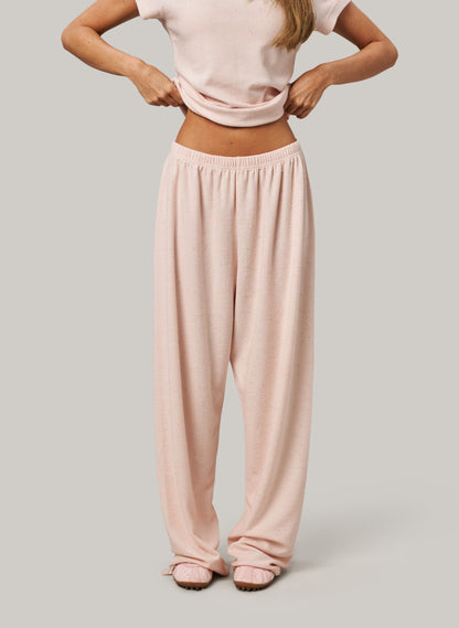 Person wearing a light pink top and matching pants on a neutral background