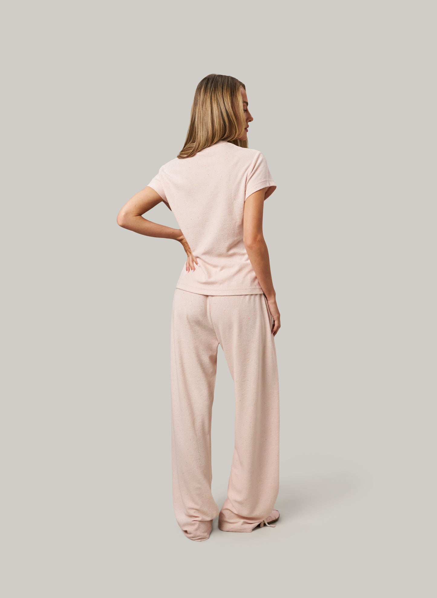 Woman wearing a pink outfit standing against a plain background