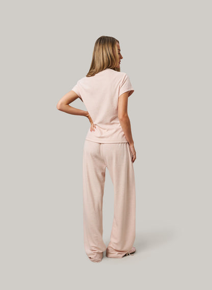 Woman wearing a pink outfit standing against a plain background