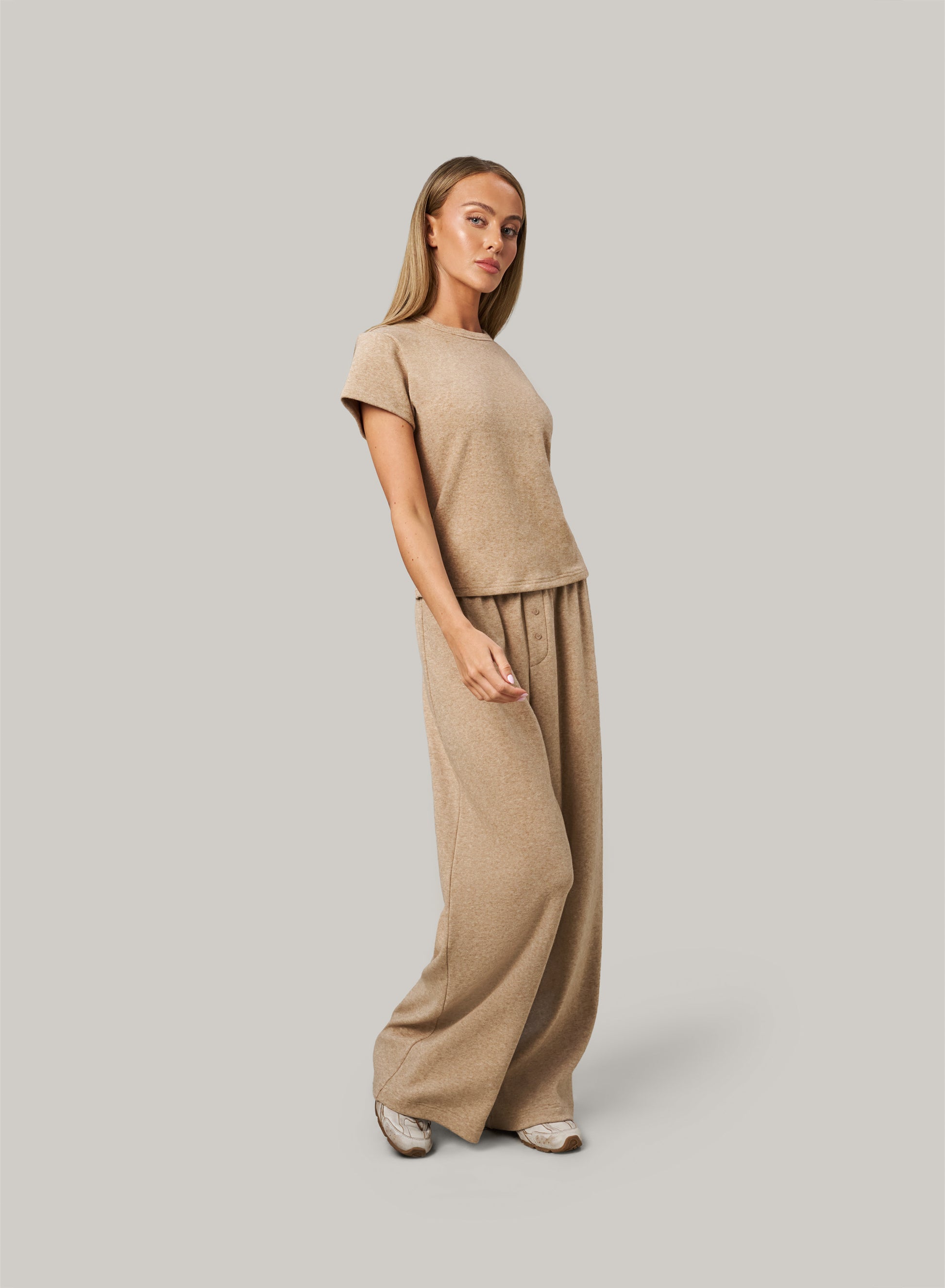 Woman wearing a beige outfit on a plain background