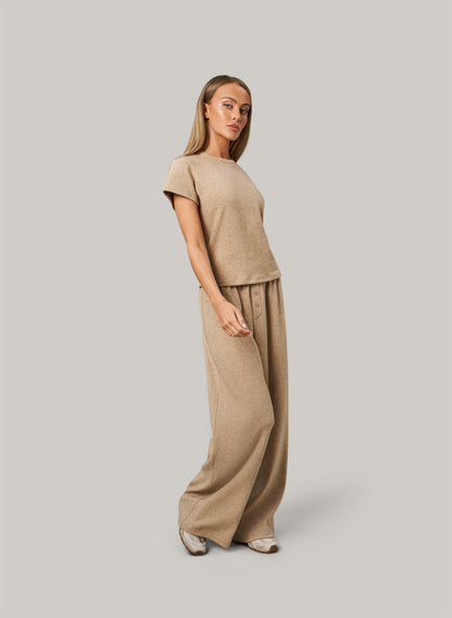 Woman wearing a beige outfit on a plain background