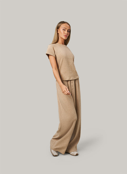 Woman wearing a beige outfit on a plain background