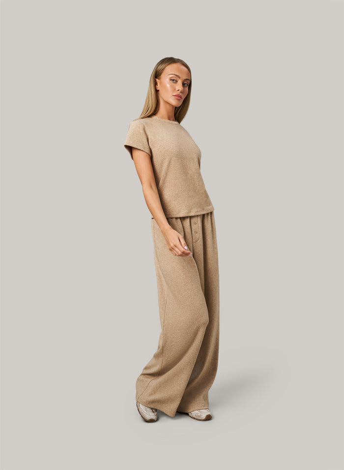 Woman wearing a beige outfit on a plain background