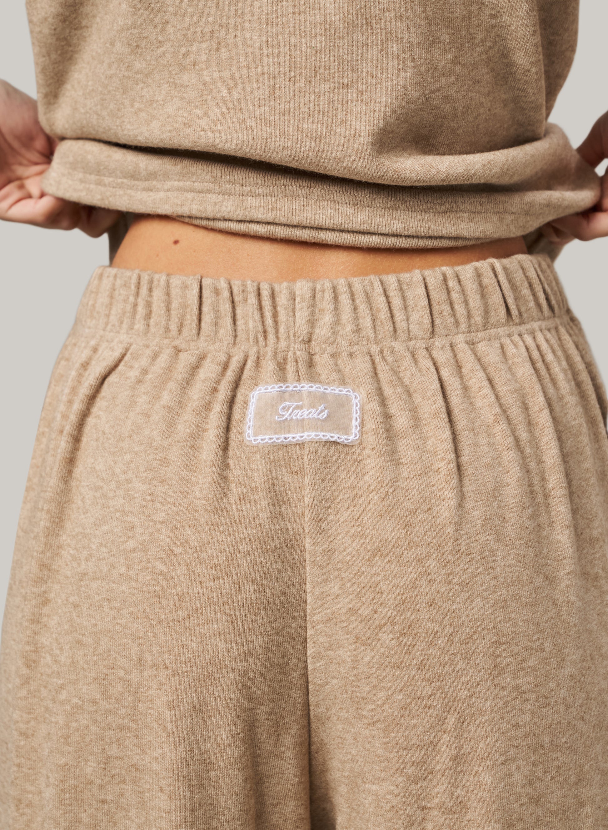 Beige sweatpants with a brand label on a neutral background