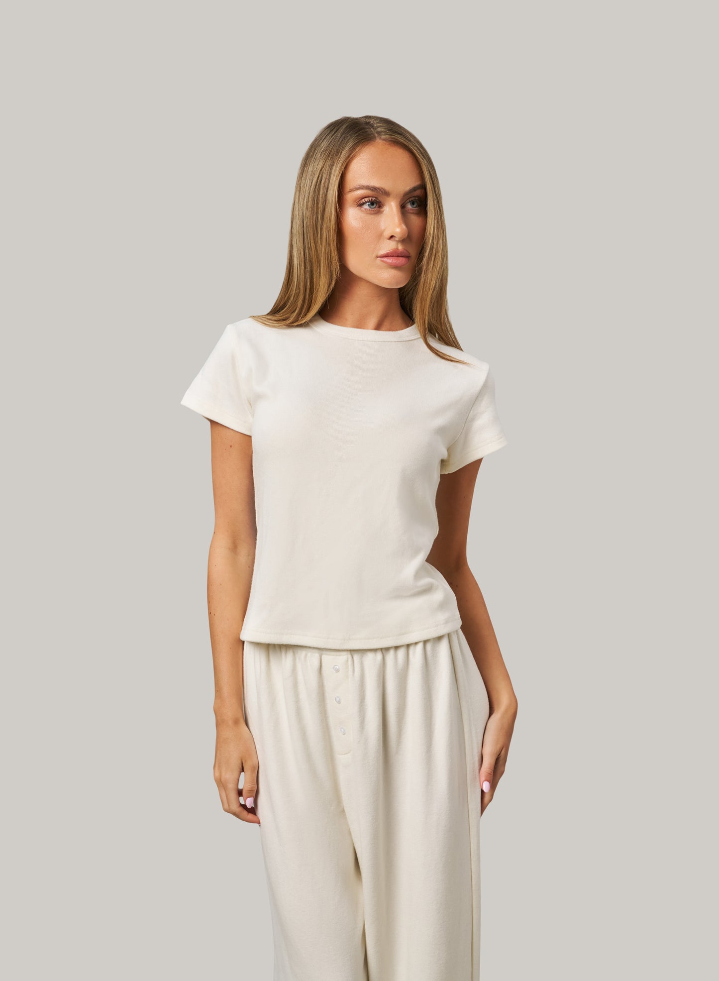 Woman wearing a white set against a grey background