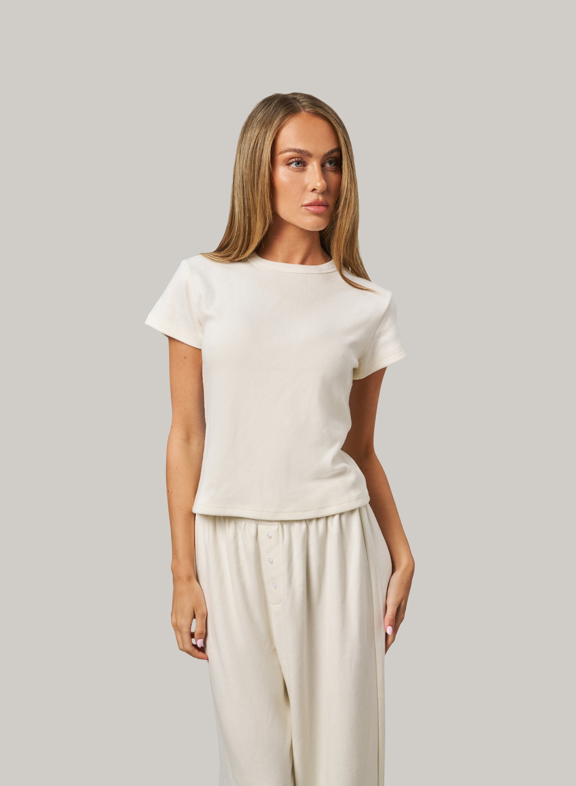 Woman wearing a white set against a grey background