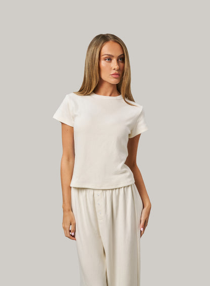 Woman wearing a white set against a grey background