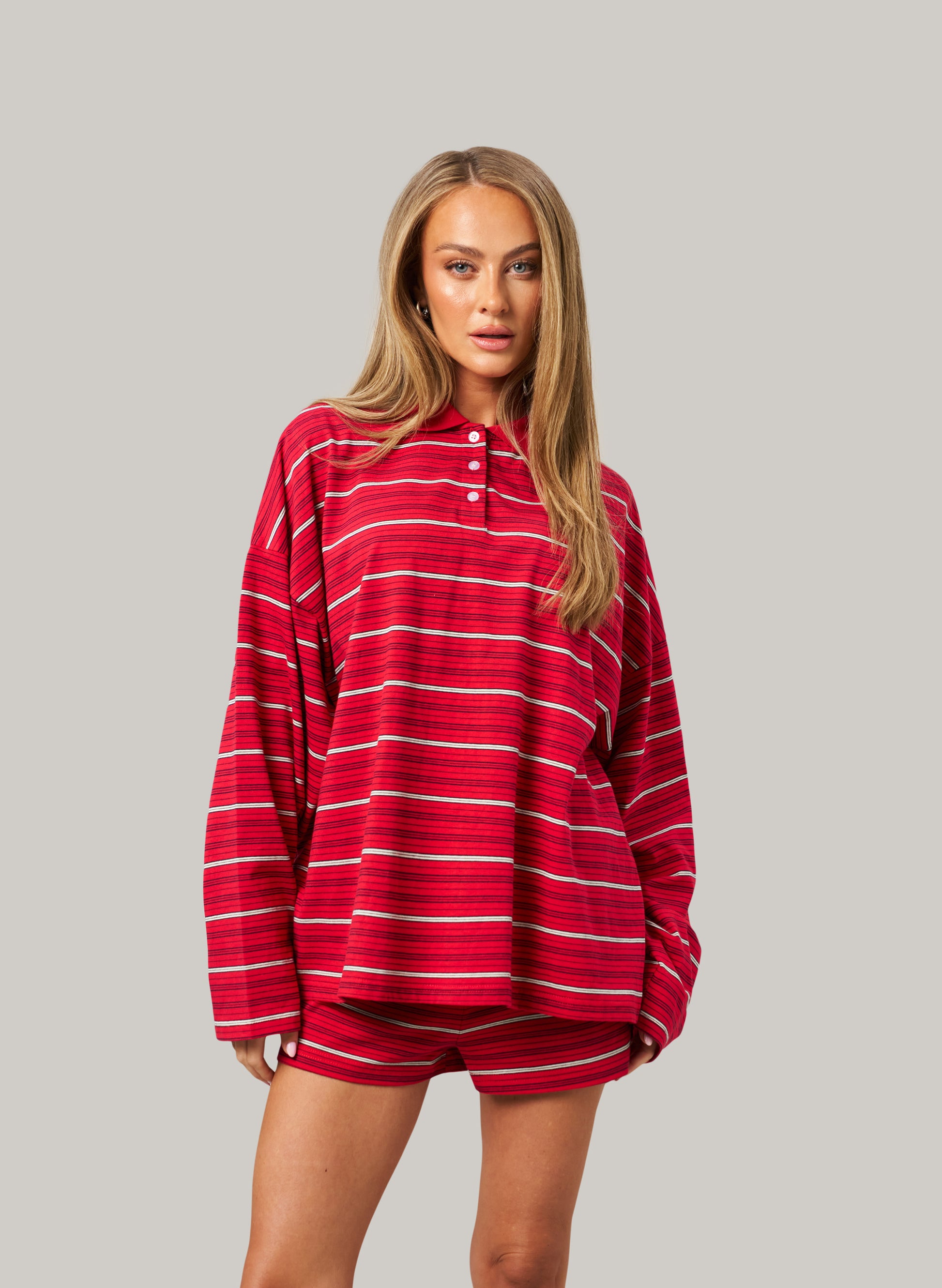 Woman wearing a red and white striped shirt with shorts on a gray background