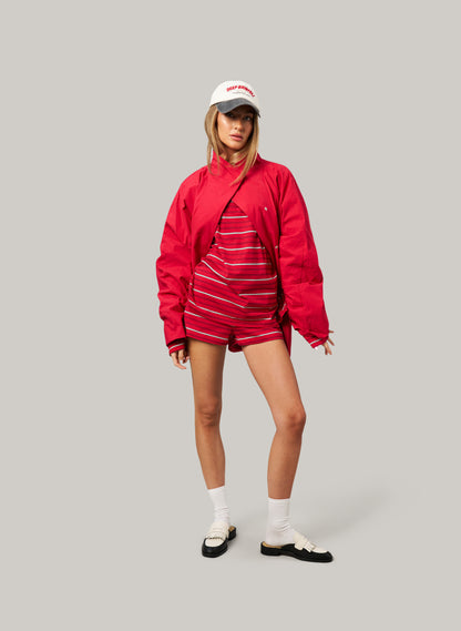 Person wearing a red outfit with a matching jacket, striped shirt, and shorts on a gray background