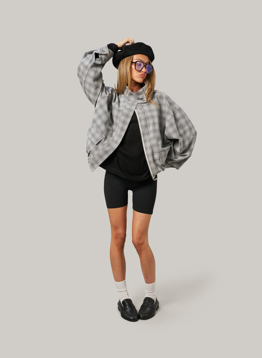 Person wearing a plaid shirt, black beret, and black shorts on a plain background