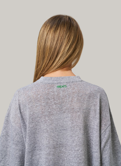 Person wearing a gray sweatshirt with 'TREATS' logo on the back against a plain background