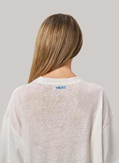 Person wearing a light gray sweatshirt with 'TREATS' logo on the back against a plain background