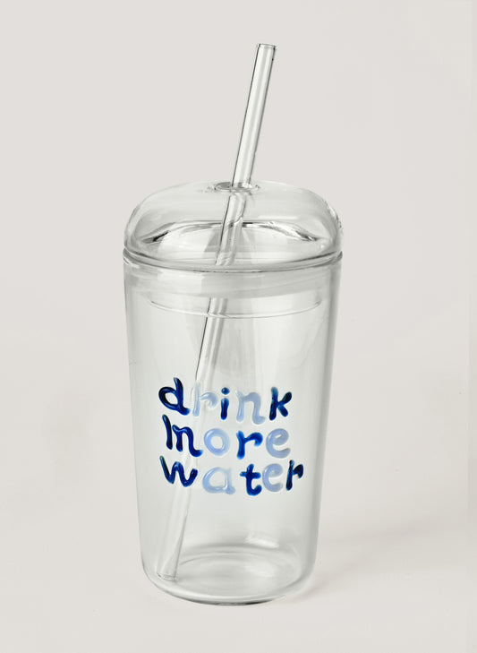 Clear tumbler with blue text 'drink more water' and a straw on a light gray background
