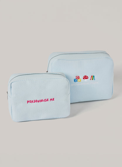 Light blue personalized toiletry bags set with embroidered “PERSONALISE ME” text on the small pouch and “MY FAVOURITE THINGS” with playful icons on the larger pouch