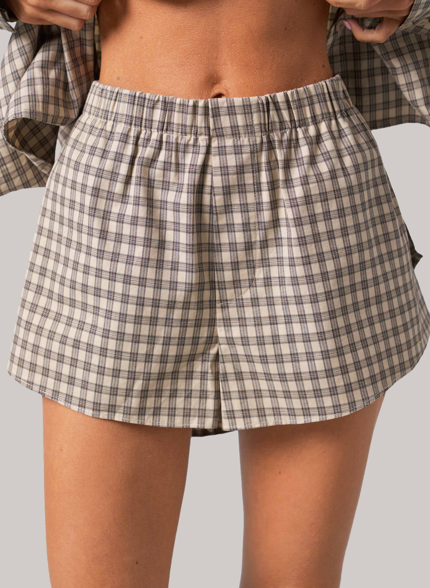 Person wearing plaid shorts on a plain background