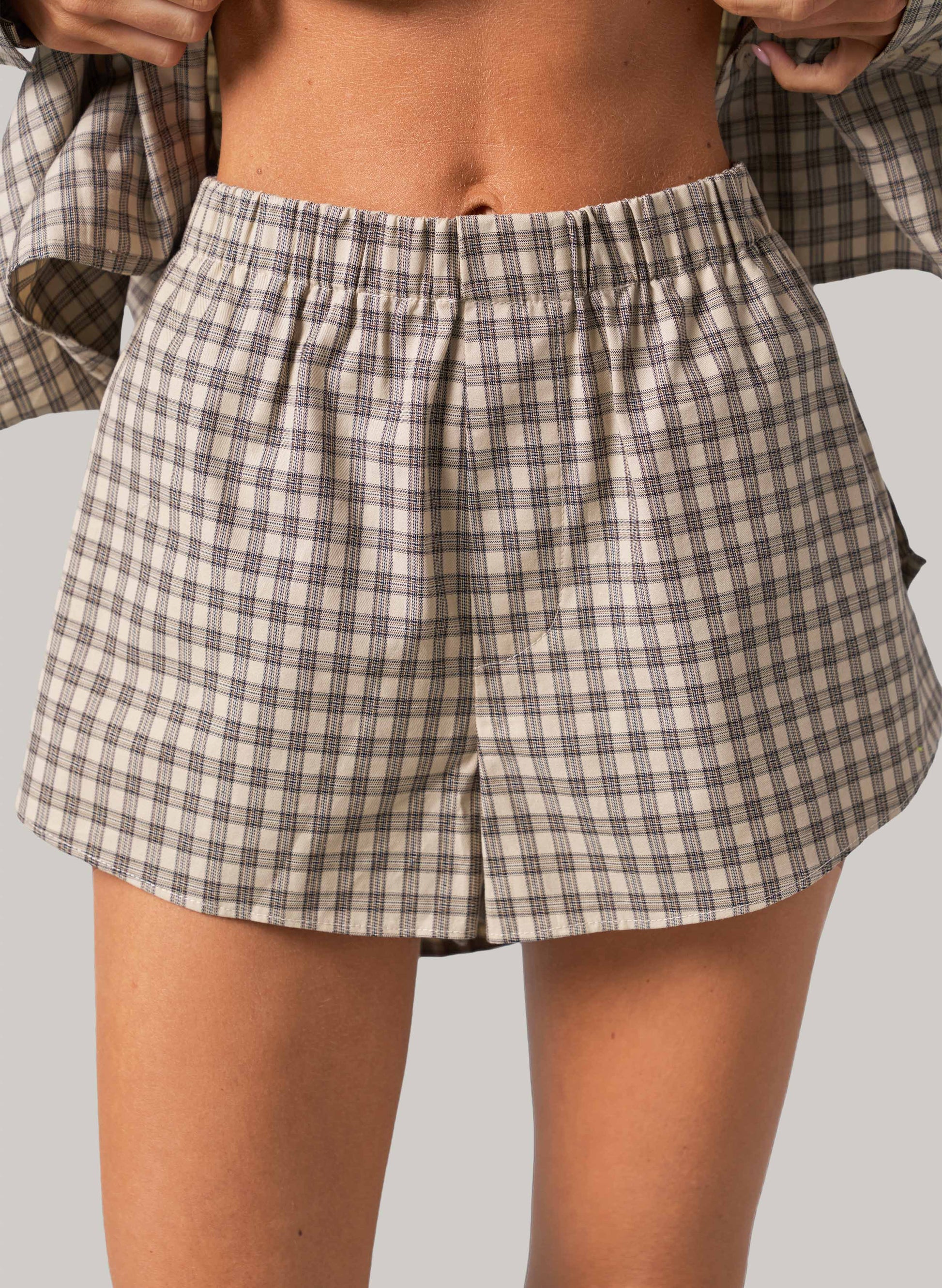 Person wearing plaid shorts on a plain background