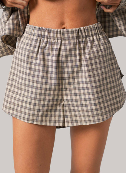 Person wearing plaid shorts on a plain background