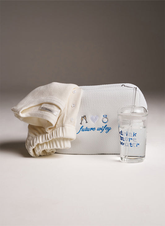 women's white set with white waffle bag with embroidery saying 'future wifey' on. Stood up next to it a glass saying 'drink more water'