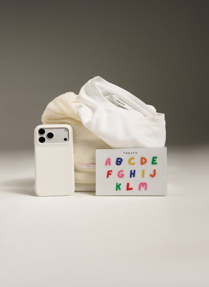 White socks and phone case with colorful alphabet card on a neutral background