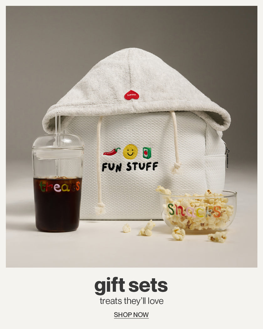 White hoodie with colorful text, a glass of juice, and a bowl of popcorn on a gray background.