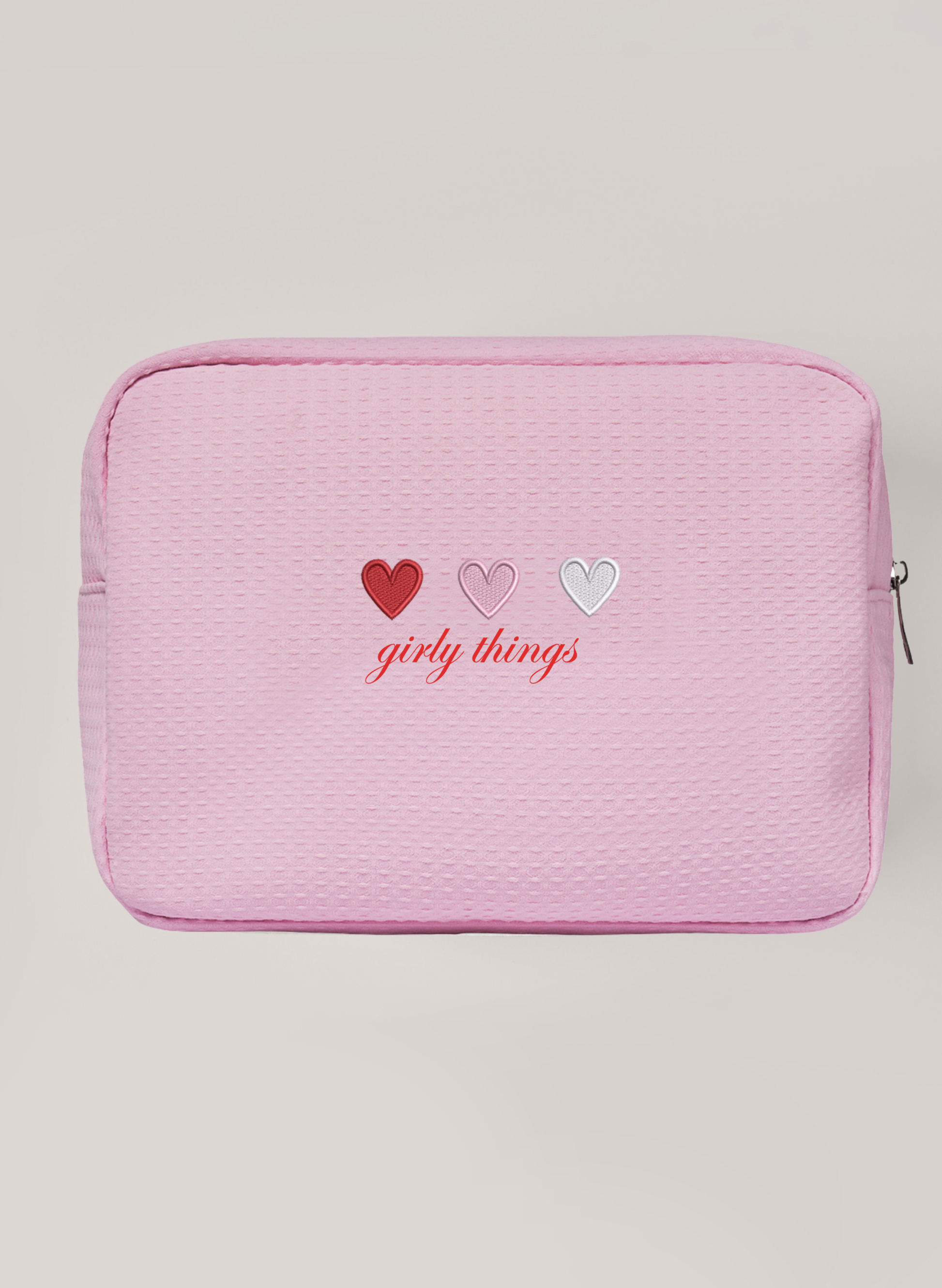 Pink waffle pouch with 'girly things' text and heart designs on a light grey background