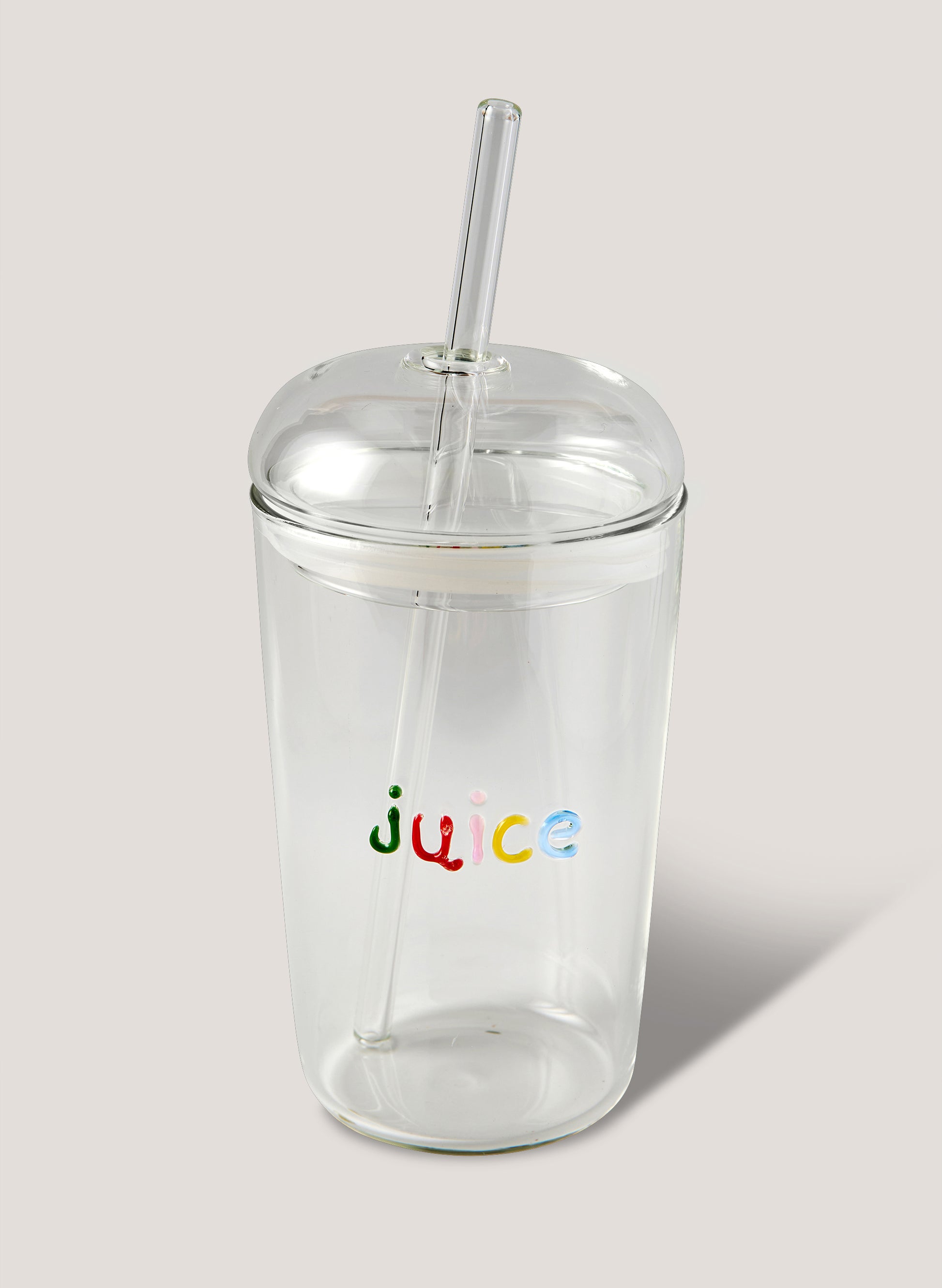 Clear tumbler with colorful 'juice' text and straw on a light background