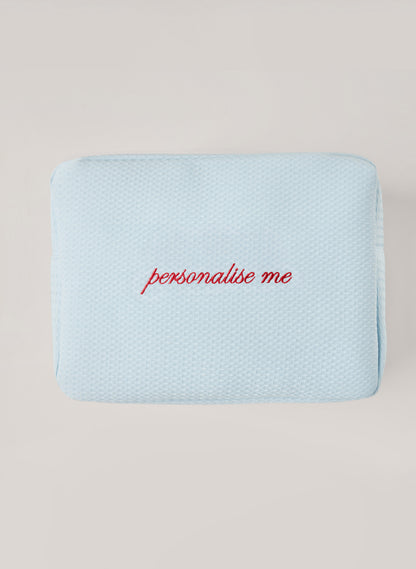 Light light blue waffle-textured pouch with zipper closure, featuring a red embroidered heart and the words 'personalise me’ on the front