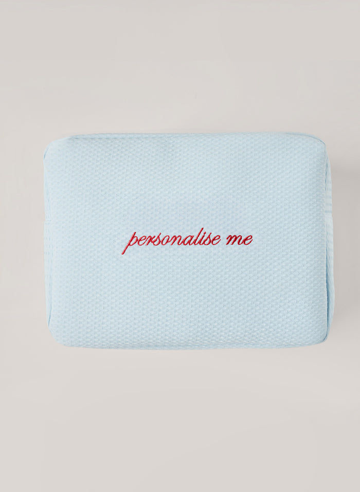 Light light blue waffle-textured pouch with zipper closure, featuring a red embroidered heart and the words 'personalise me’ on the front