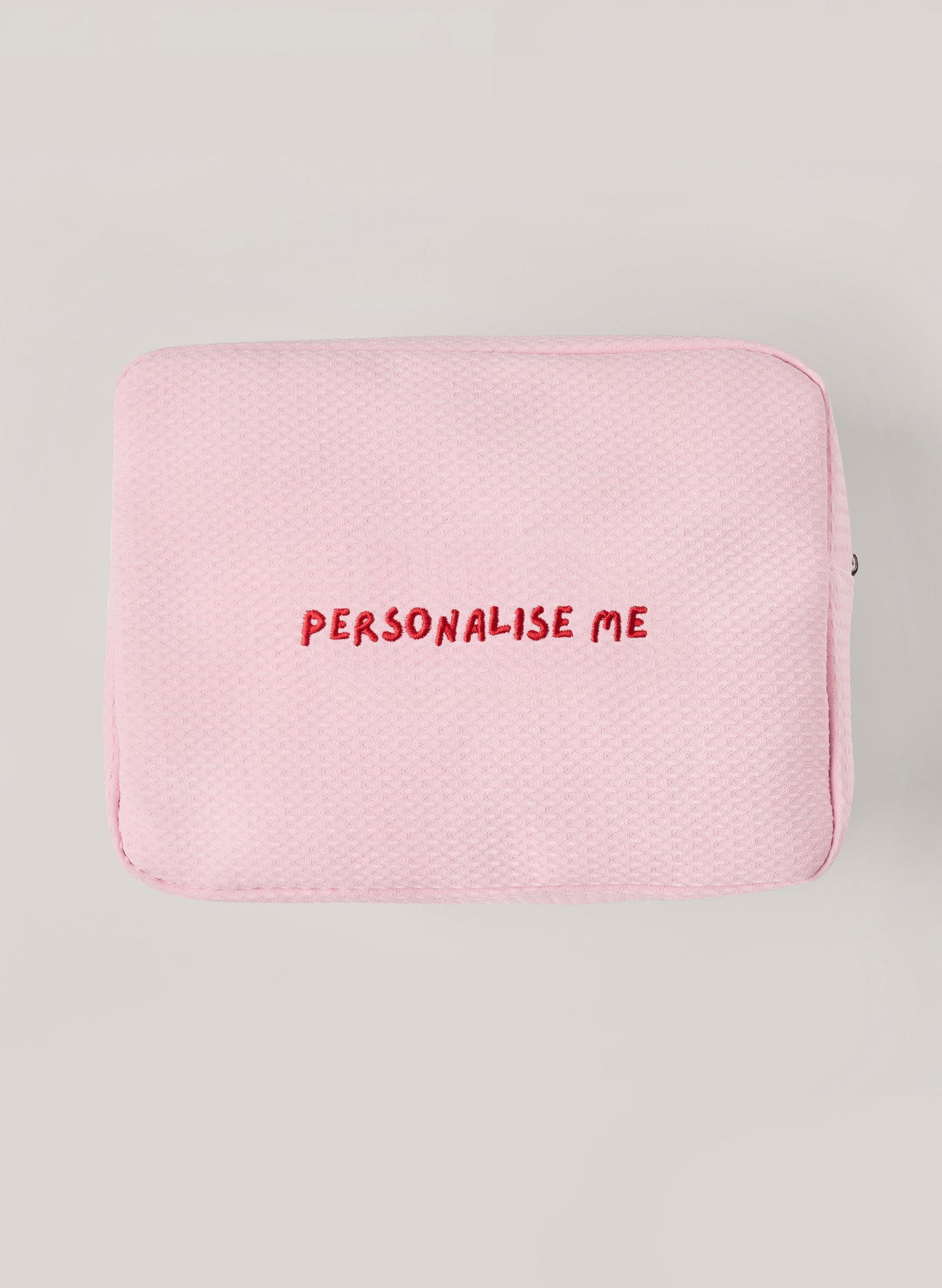 Light pink waffle-textured pouch with zipper closure, featuring a red embroidered heart and the words 'personalise me’ on the front