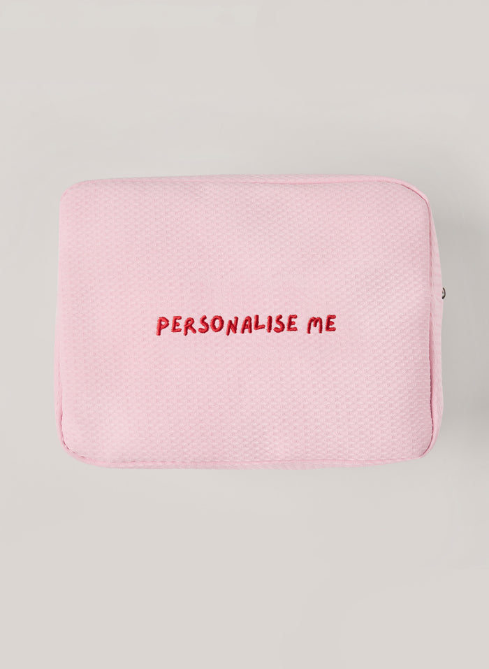 Light pink waffle-textured pouch with zipper closure, featuring a red embroidered heart and the words 'personalise me’ on the front