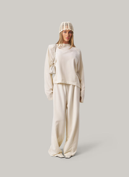 Person wearing a beige outfit with a knit hat on a light gray background