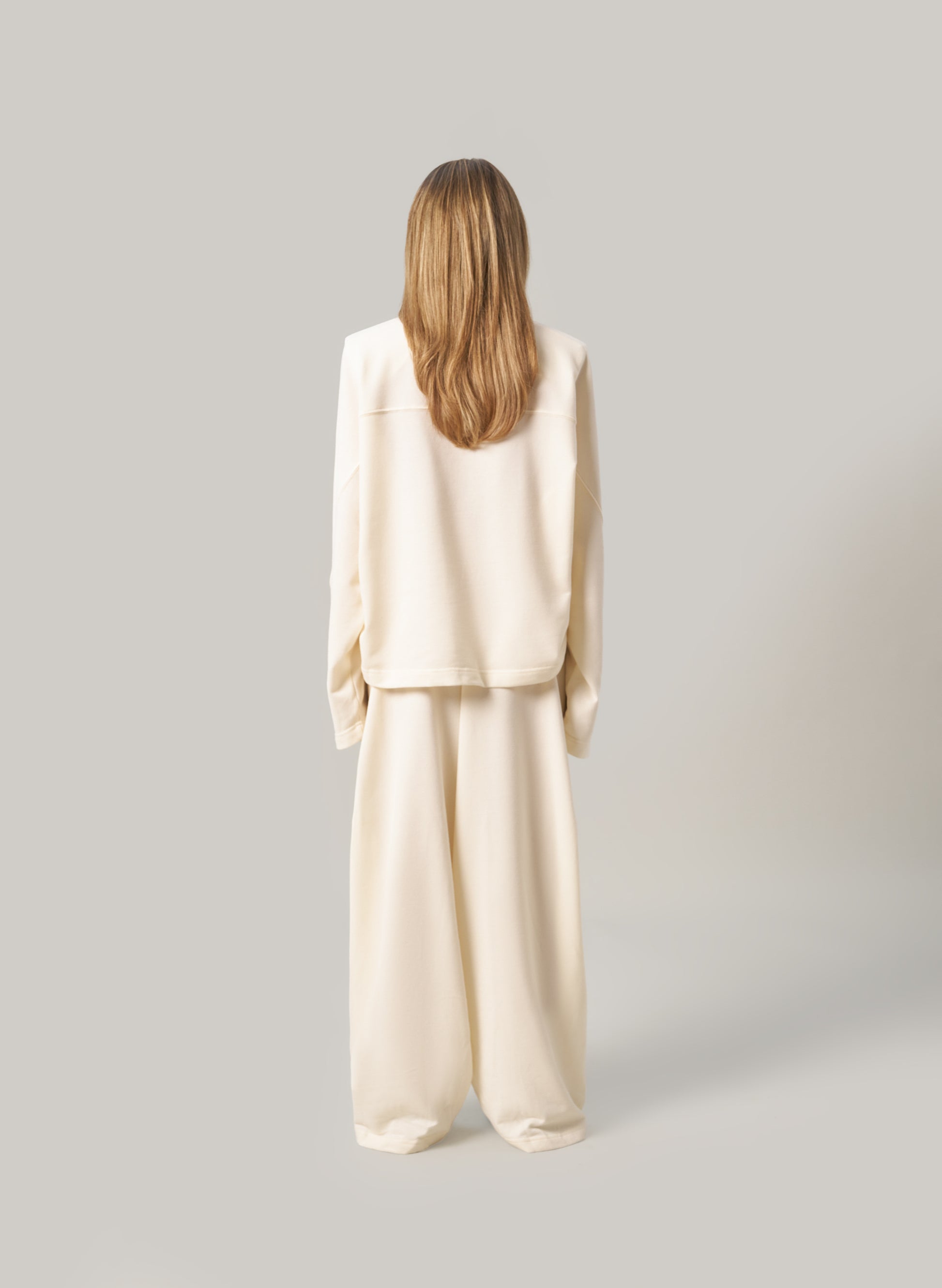 Person wearing a cream-colored outfit on a plain background