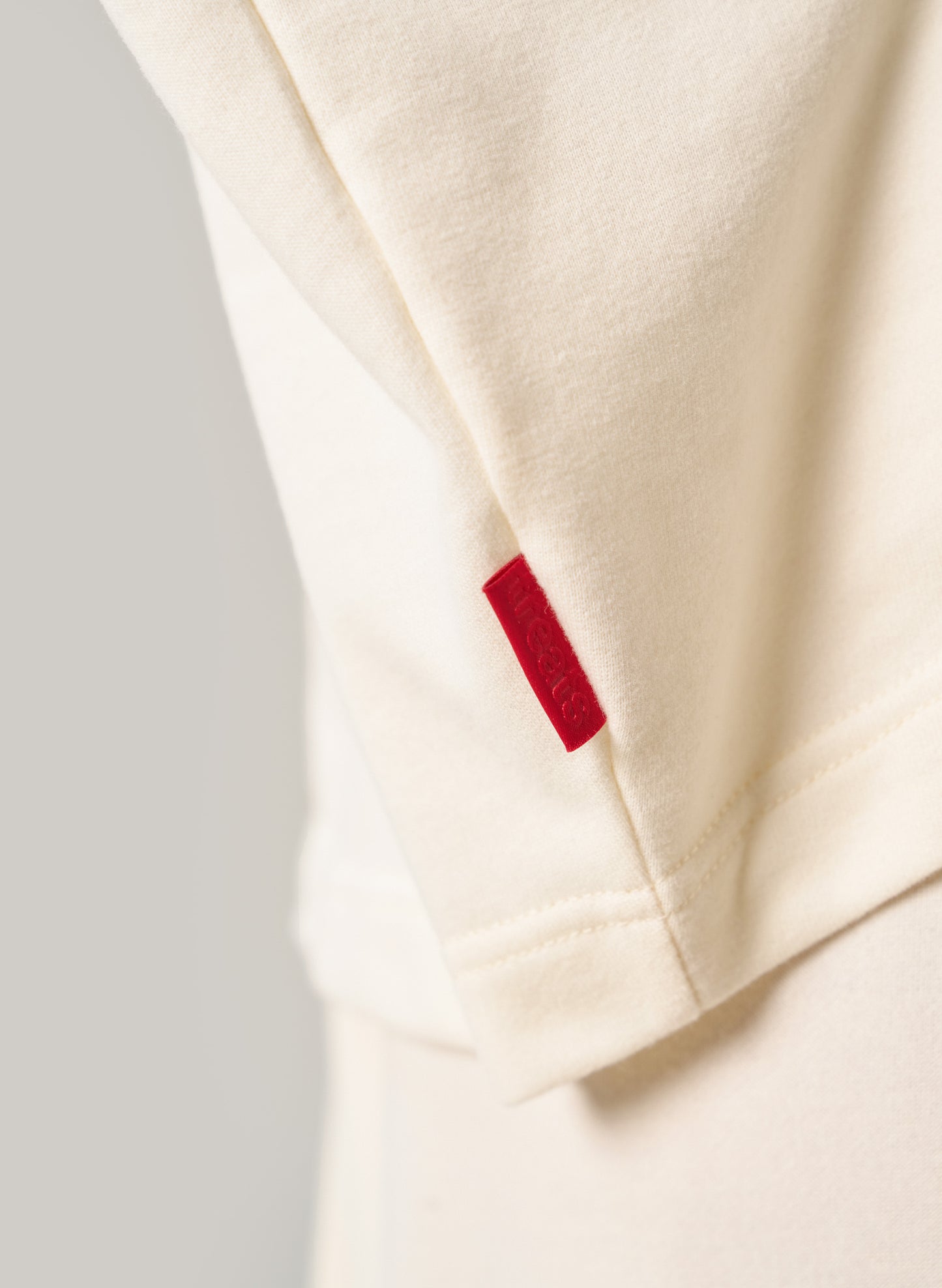 Close-up of a beige fabric with a red label on a light grey background