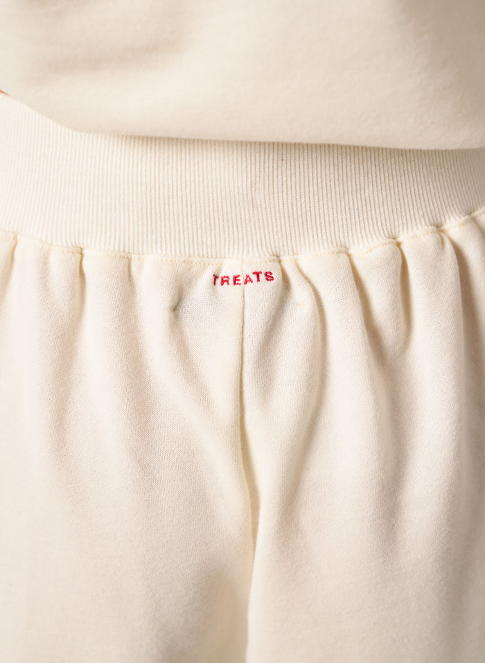 Close-up of beige fabric with 'TREATS' embroidered on it.