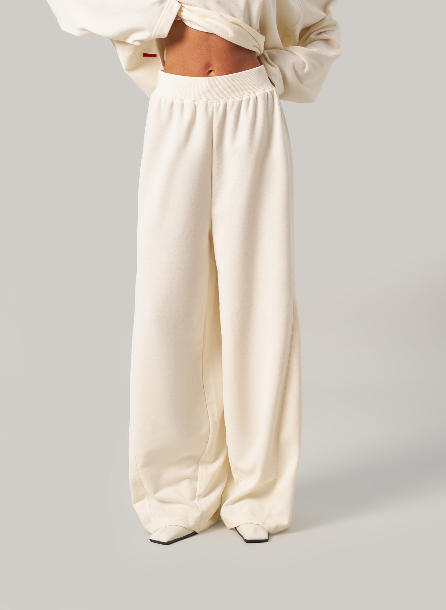 Person wearing cream-coloured pants and a matching top on a light grey background