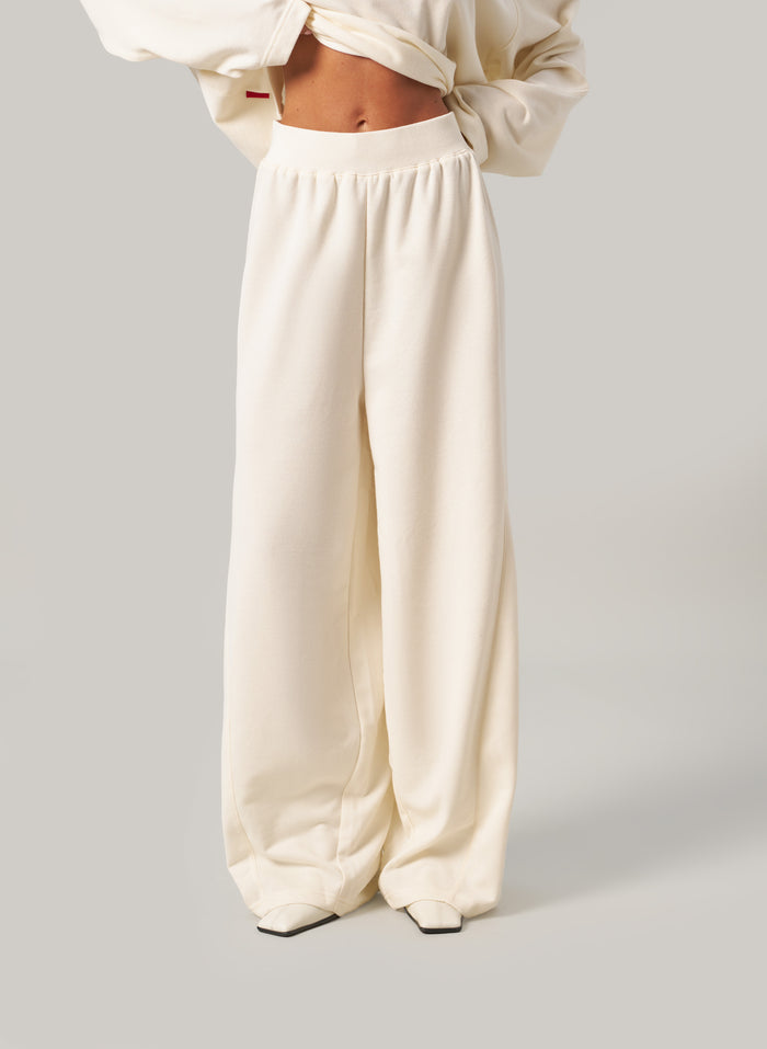 Person wearing cream-coloured pants and a matching top on a light grey background