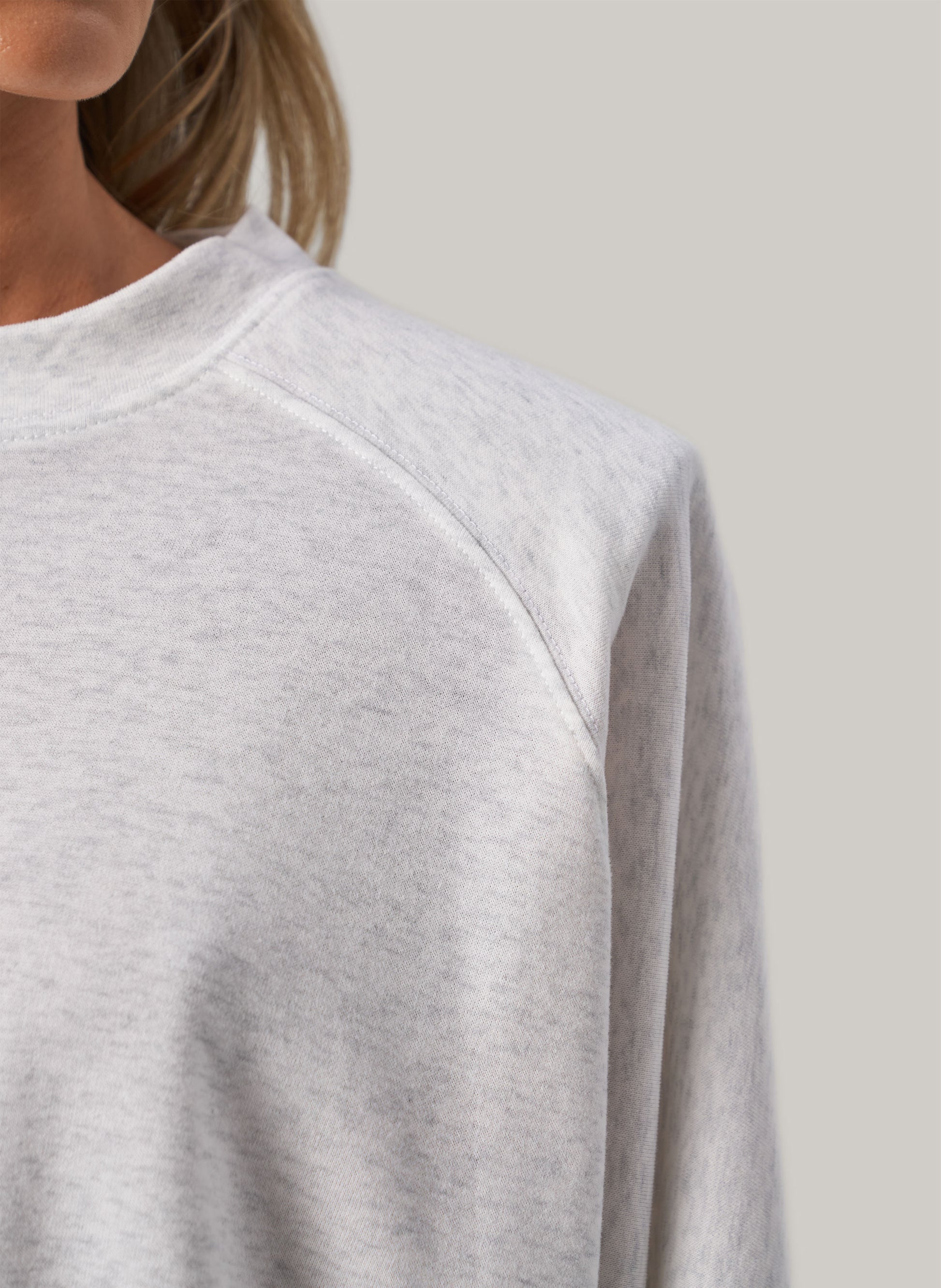 Gray sweatshirt worn by a person on a plain background