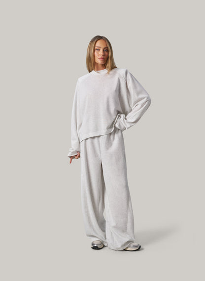 Person wearing a light grey outfit on a plain background