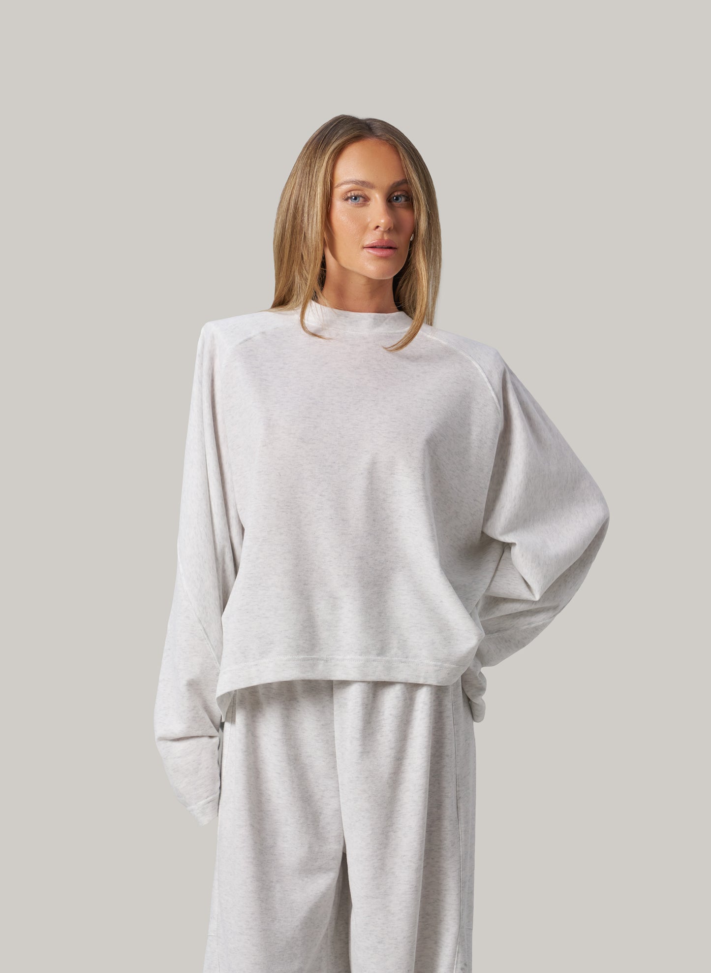 Woman wearing a light grey outfit against a plain background
