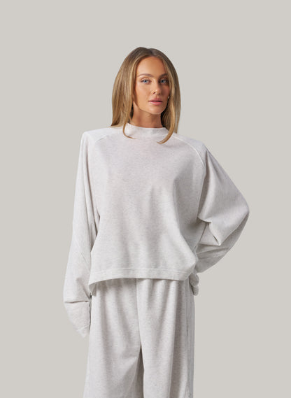Woman wearing a light grey outfit against a plain background