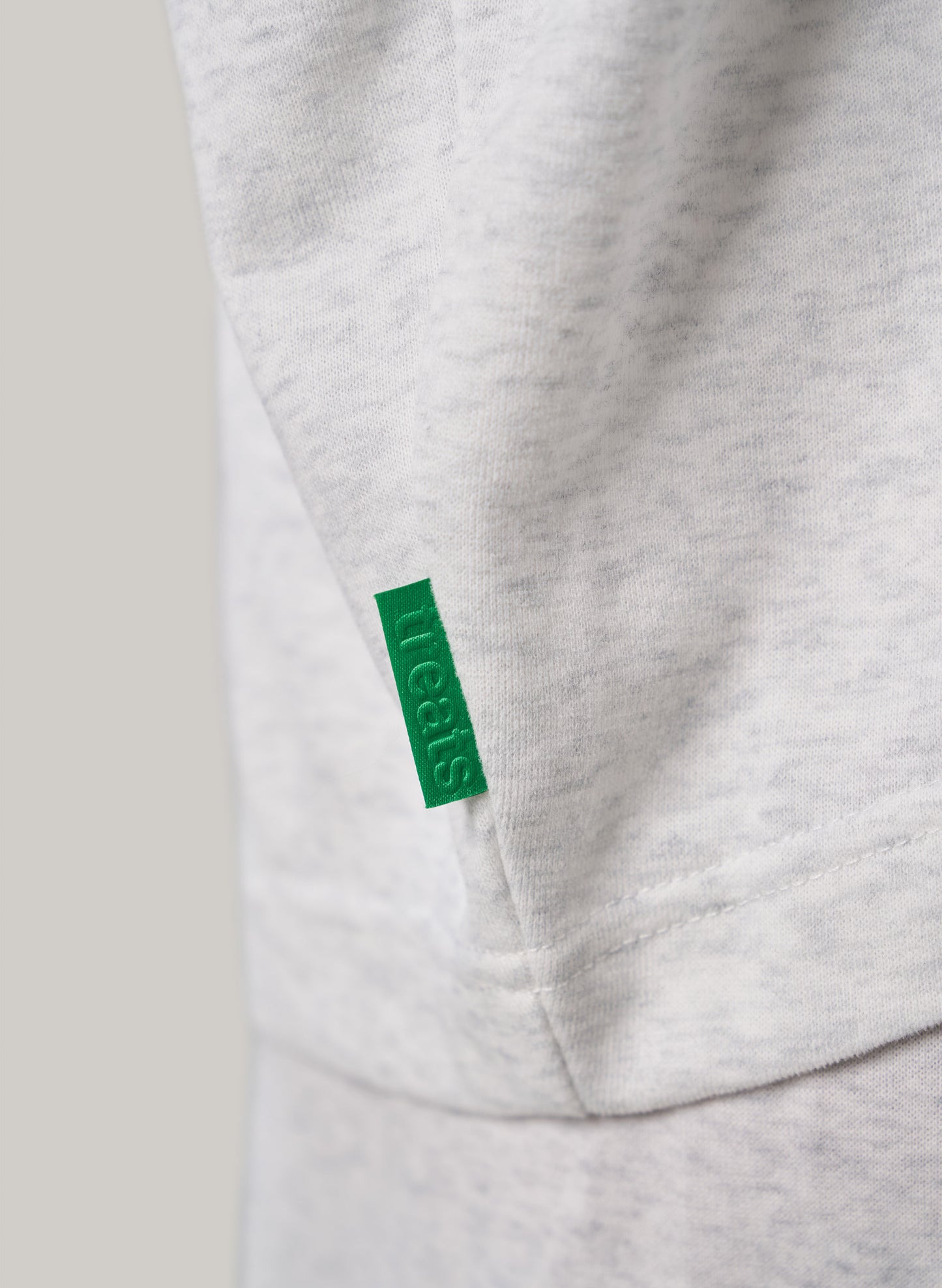 Close-up of a gray sweatshirt with a green tag on a light gray background