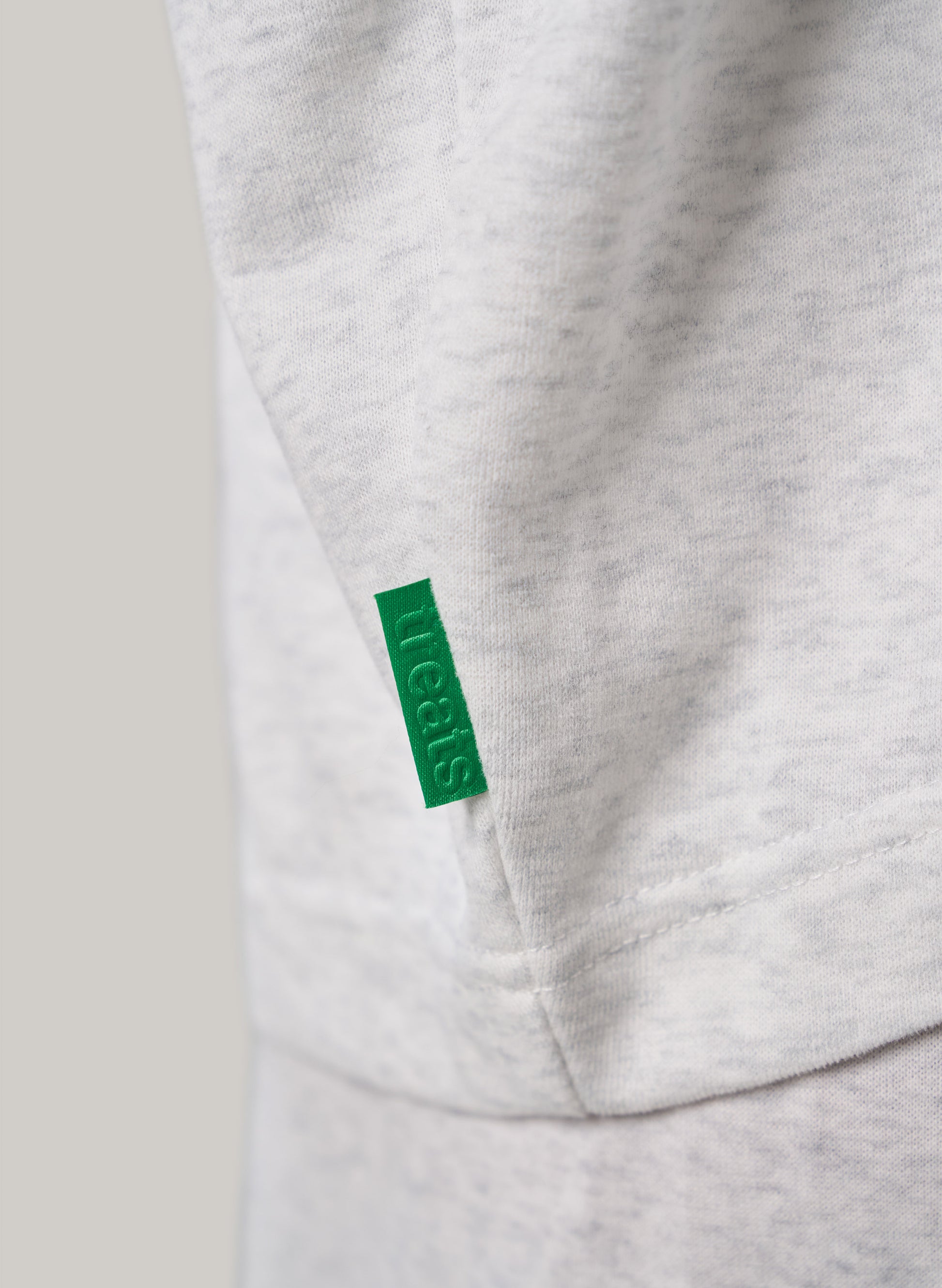 Close-up of a gray sweatshirt with a green tag on a light gray background